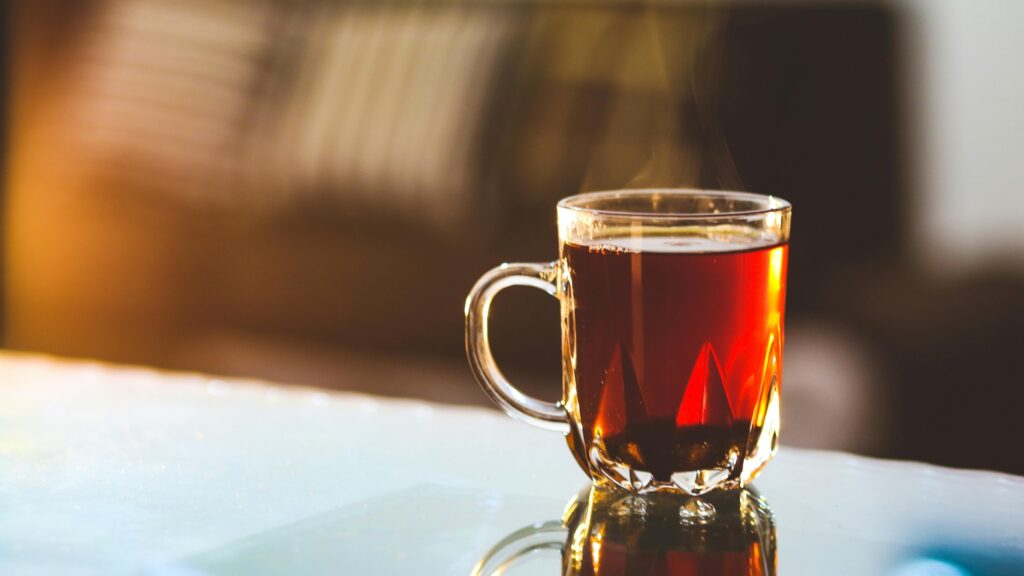 A glass cup of steaming hot tea on a table